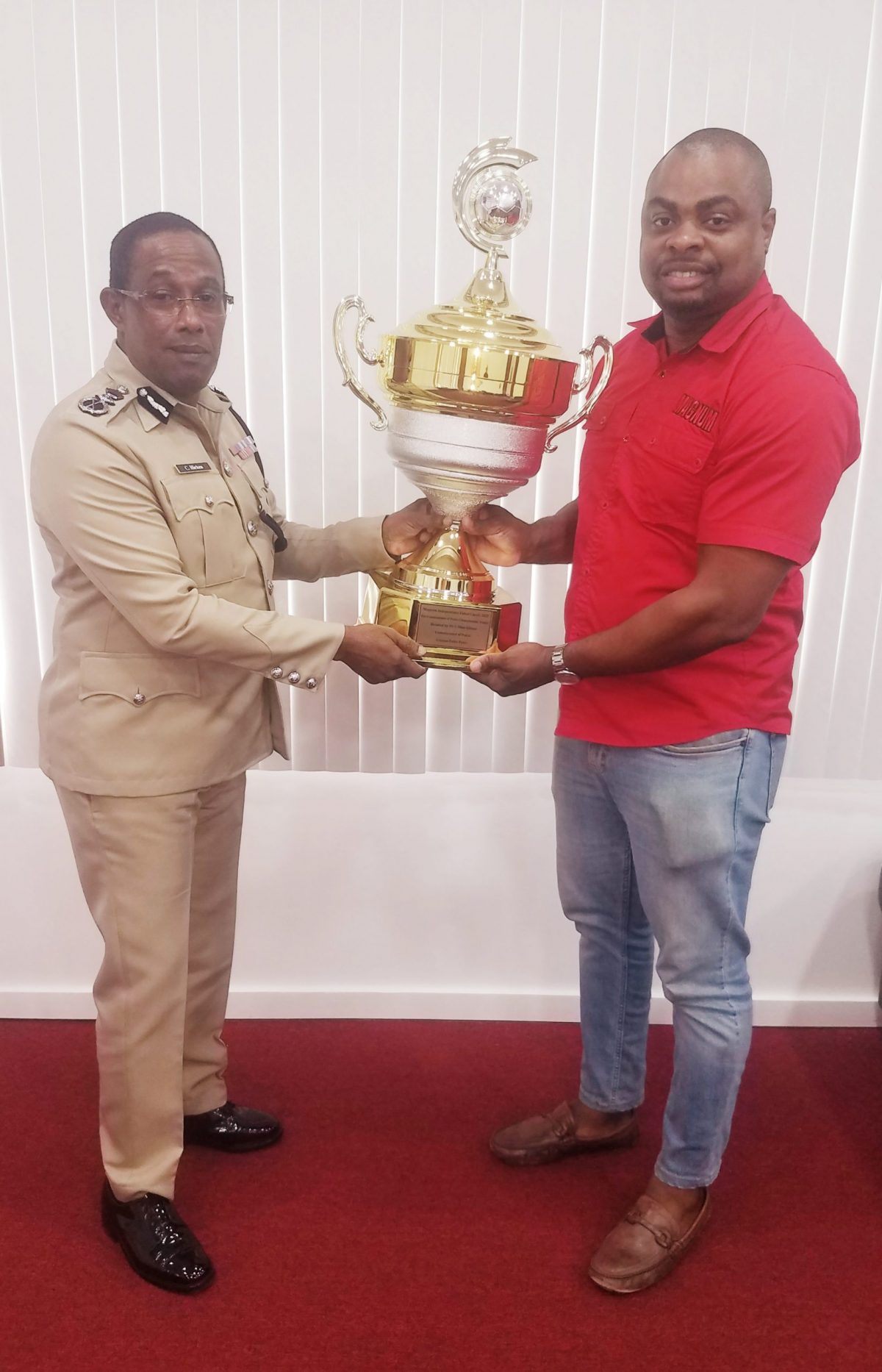 Commissioner of Police Clifton Hicken (Ag.) (left) hands over
‘The Commissioner of Police Championship Trophy’ to organizer Edison Jefford for the Magnum Independence Football Cup.