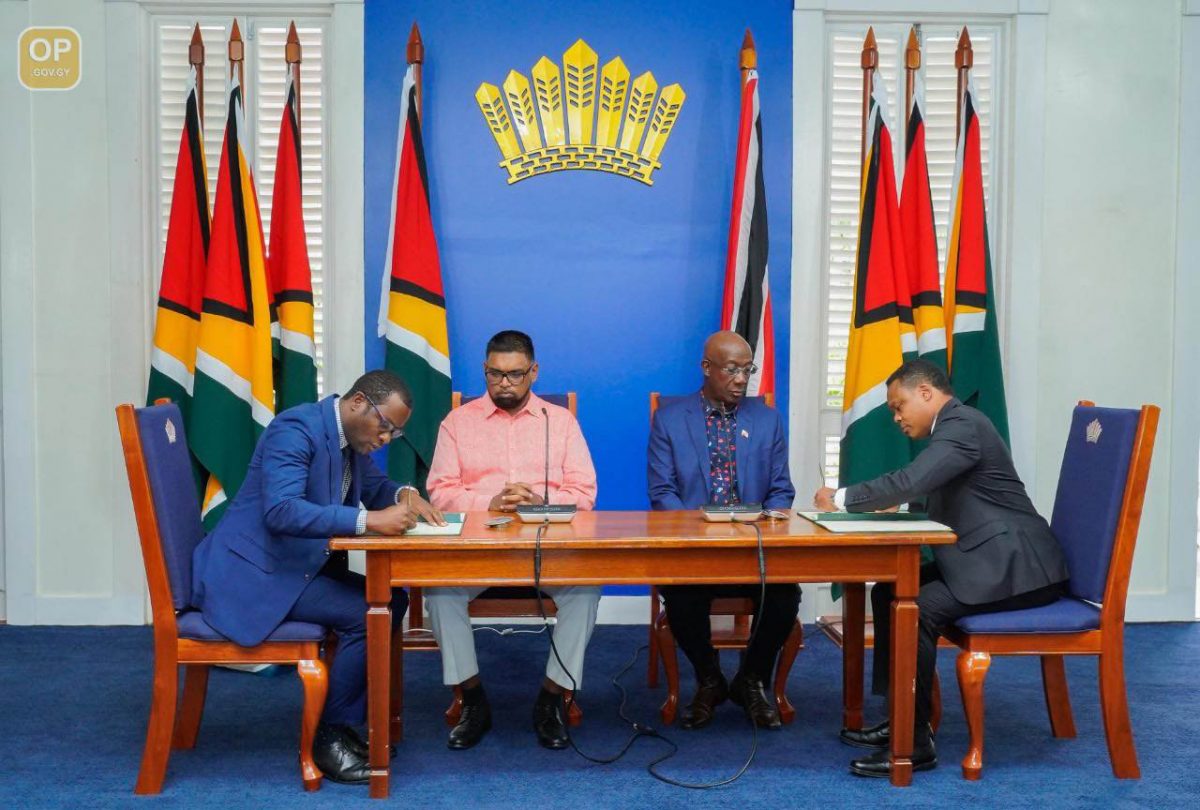 Signing on: Guyana foreign Affairs Minister Hugh Todd and his Trinidad and Tobago counterpart Amery Browne sign the MOU in the presence of President Ali and Prime Minister Rowley 