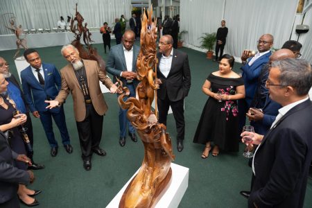 Guyanese sculptor Winslow Craig (arms outstretched) has the rapt attention of invitees to the State Dinner at State House on Saturday for delegates to the agricultural investment conference. Craig curated an art exhibition prior to the dinner and provided explanations on the exhibits. (Office of the President photo)