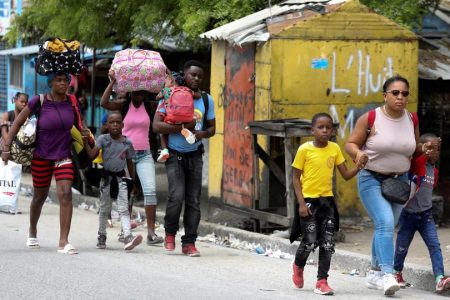 Residents carry their belongings as they flee their homes due to ongoing gun battles between rival gangs, in Port-au-Prince, Haiti, May 2, 2022. (Reuters)