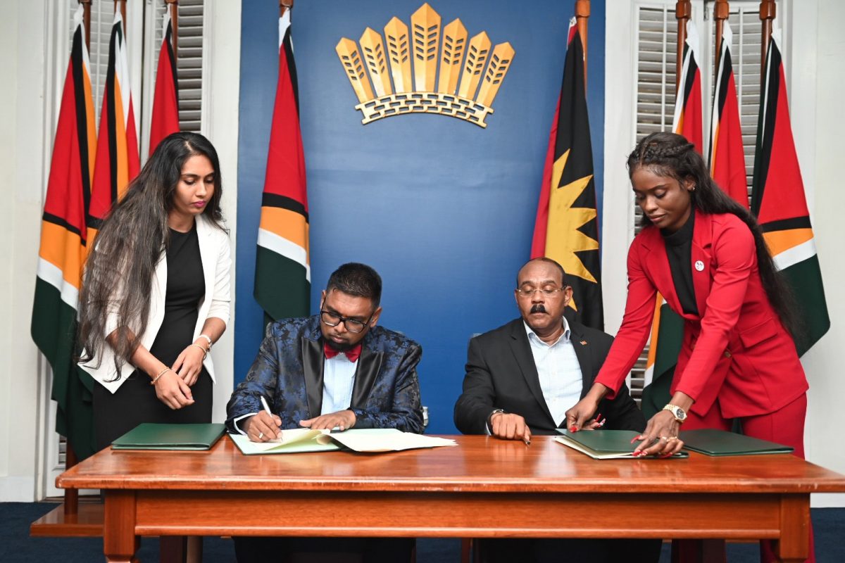 President Irfaan Ali (seated at left) signing the MoU. Seated at right is Antigua and Barbuda Prime Minister, Gaston Browne. (Office of the President photo)