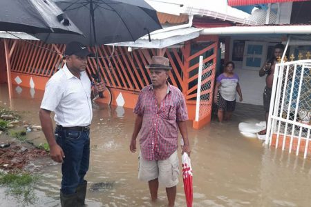 Region Five Chairman Vickchand Ramphal (left) interacting with flood-affected villagers