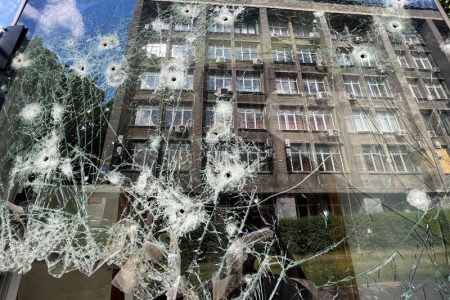 A building is reflected in a shop window at a residential area after a shelling with cluster ammunition, as Russia's attack on Ukraine continues, in Kharkiv, Ukraine May 23, 2022. REUTERS/Ivan Alvarado
