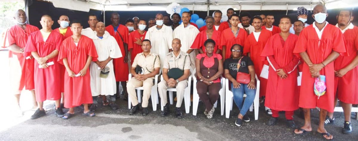 Director of Prisons (ag) Nicklon Elliot (seated second from left) and prison officials pose with some of the inmates who graduated