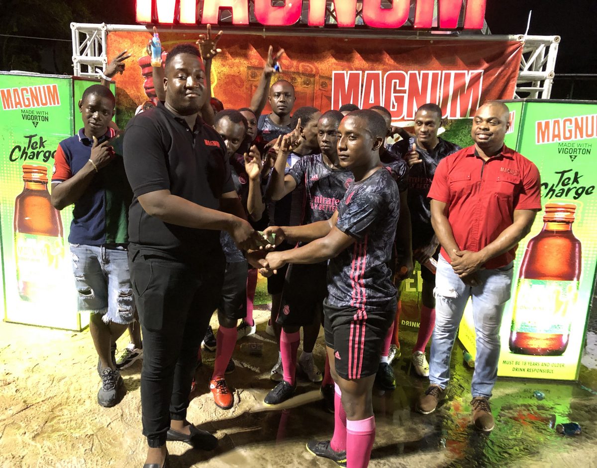 Back Circle Captain Stephon Reynolds (right) receiving the first place prize money from Jamal Baird, Magnum Brand Manager, in the presence of teammates and supporters, following the conclusion of the tournament