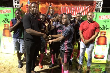 Back Circle Captain Stephon Reynolds (right) receiving the first place prize money from Jamal Baird, Magnum Brand Manager, in the presence of teammates and supporters, following the conclusion of the tournament
