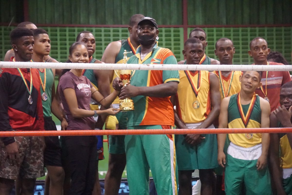 Pugilists of the GDF gym along with Best Coach, Terrence Poole, receive the Best Gym trophy after racking up 16 points during the three-night Andrew Lewis National Novices Championships which concluded on Sunday night at the National Gymnasium. (Emmerson Campbell photo)