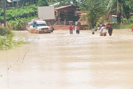 Public-spirited residents transporting a patient by foot to the airstrip as the ambulance could not navigate the waters. (Photo courtesy of Shaun Britton)