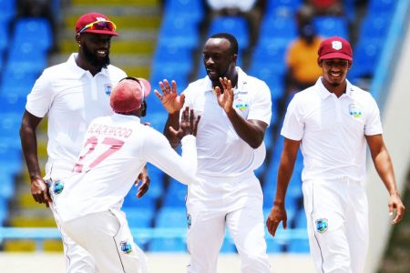 Seamer Kemar Roach (right) celebrates a wicket yesterday with Jermaine Blackwood and Raymon Reifer (left). 