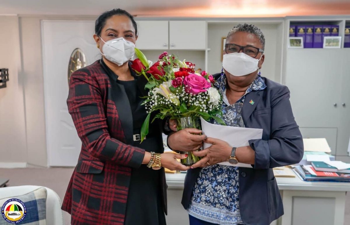 Ann Greene (right) receiving a bouquet from Minister Persaud. 