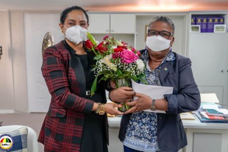 Ann Greene (right) receiving a bouquet from Minister Persaud. 