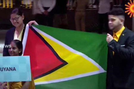 Guyana is among 187 teams participating in the 2022 Chess Olympiad in Chennai, India. In this screenshot from Tamil TV station Sun News, 2022 Women's Champion Pooja Lam (left) and player Roberto Neto bear the Guyana flag.  