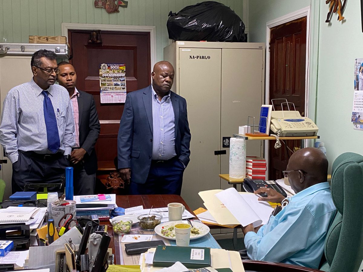 Leader of the Opposition Aubrey Norton (third from left) and AFC Leader Khemraj Ramjattan (left) engaging Clerk of the National Assembly (seated) Sherlock Isaacs 