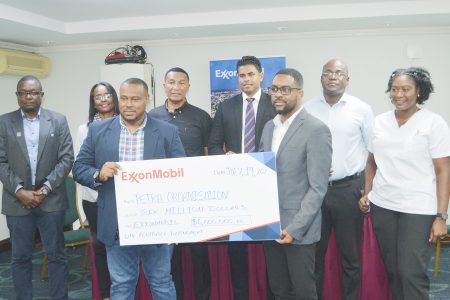 Petra Organization Co-Director Troy Mendonca (left) collecting the sponsorship cheque from ExxonMobil Community Relations Advisor Ryan Hoppie. Also in the photo (back row from left) GFF Assistant Technical Director Bryan Joseph, Assistant Director of Sports Melissa Dow-Richardson, NSC Chairman Kashif Muhammad, Minister of Culture, Youth and Sport Charles Ramson, Dr Olatto Sam, Education Specialist in the office of the Minister of Education, and Petra Organization Senior member Jacklyn Boodie