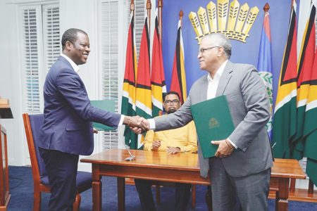 From left (standing), Guyana’s Minister of Foreign Affairs Hugh Todd  and Belize’s Minister of Foreign Affairs, Foreign Trade and Immigration, Eamon Courtenay shaking hands on the deal. Sitting in the background is President Irfaan Ali. (Office of the President photo)