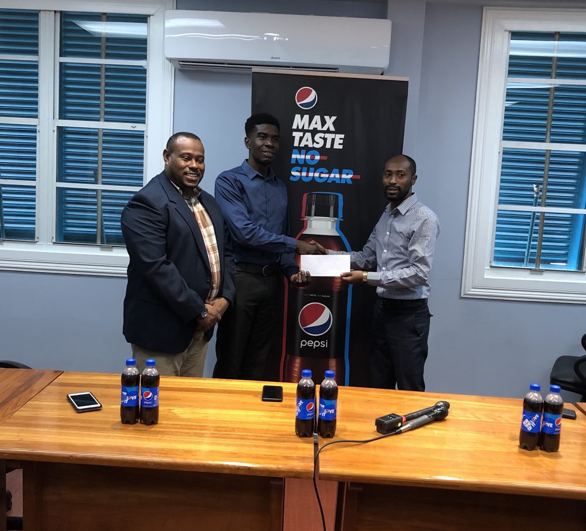 Larry Wills (left), Pepsi Brand Manager, hands over the sponsorship to Petra Organization member Mark Alleyne in the presence of Co-Director Troy Mendonca
