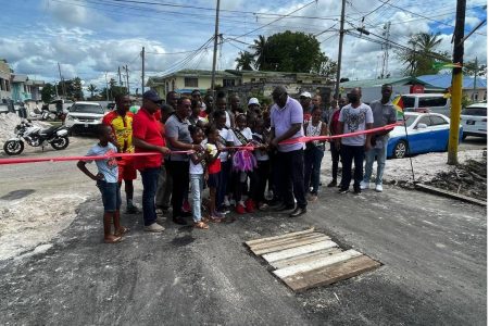 Minister of Home Affairs Robeson Benn cutting the ceremonial ribbon along side Commissioner of Police Clifton Hicken and residents of the community to Back Circle to official open the newly minted recreational square.  
