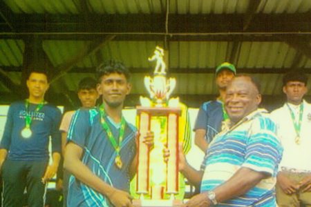 Tournament coordinator James Lewis (right) hands over the championship trophy to the captain of Hope Secondary.