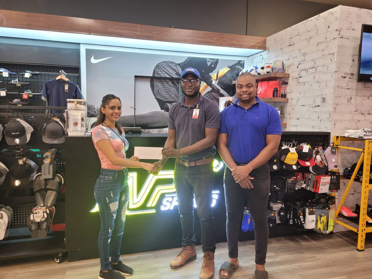 Annalisa Banwarie (left), MVP Sports Store Supervisor, presents the sponsorship to Ballers Entertainment Vice President Clayton Reece in the presence of Sports Management Inc.,’s Edison Jefford.