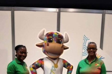 Dr. Karen Pilgrim (right), the Chef de Mission of Team Guyana’s delegation to the Commonwealth Games along with General Team Manager, Nalini McKoy, pose for a Stabroek News photo with the Games mascot upon arrival in the UK.