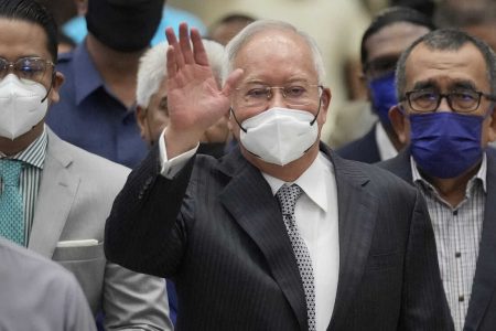 Former Malaysian Prime Minister Najib Razak, center, wearing a face mask, waves as he arrives at the Court of Appeal in Putrajaya, Malaysia, Tuesday, Aug. 23, 2022. Najib was sentenced to 12 years in jail by a high court in July 2020, after being found guilty of abuse of power, criminal breach of trust and money laundering for illegally receiving 42 million ringgit ($9.4 million) from SRC International, a former unit of 1MDB. (AP Photo/Vincent Thian)