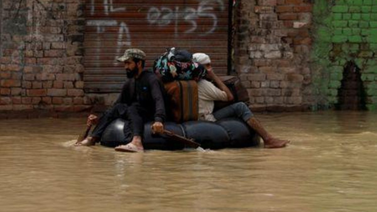 A volunteer paddles an inflatable tube as he evacuates a flood victim with his belongings, following rains and floods during the monsoon season in Charsadda, Pakistan August 27, 2022. REUTERS/Fayaz Aziz