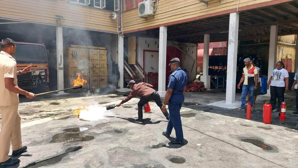 Ministry of Education security personnel being taught how to use a fire extinguisher. (GFS photo)

