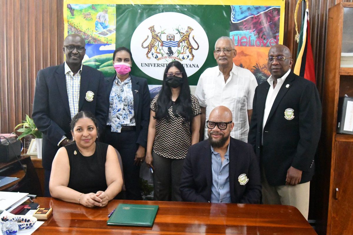 University of Guyana Vice-Chancellor, Professor Paloma Mohamed (seated left) and Pele FC Alumni Treasurer, Patrick ‘Labba’ Barton (seated right) are pictured with other UG and Pele FC Alumni members following the signing