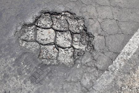 The geo-cell technology is visible due to the deterioration of the asphalt 