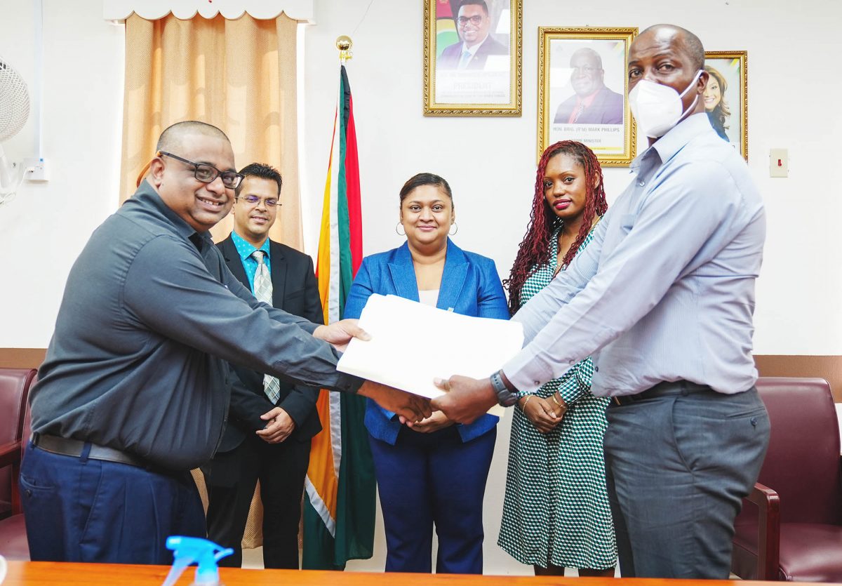 Permanent Secretary,  Alfred King (right) and Adrian Singh of Gafsons Industries Limited shaking hands on the signing. Minister of Education, Priya Manickchand is at centre.
