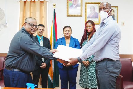 Permanent Secretary,  Alfred King (right) and Adrian Singh of Gafsons Industries Limited shaking hands on the signing. Minister of Education, Priya Manickchand is at centre.