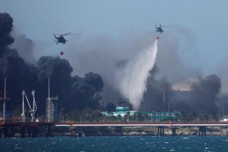 Helicopters drop water over fuel storage tanks that exploded near Cuba's supertanker port in Matanzas [Alexandre Meneghini/Reuters]