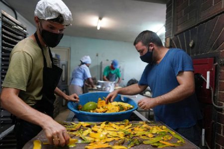 Ricardo Fernandez (R), cofounder of the Deshidratados Habana company, prepares mango skin to dry at his business in Havana, Cuba, August 15, 2022. REUTERS/Alexandre Meneghini