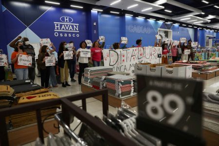 Demonstrators hold a sign that reads "Dictatorship never again" during a protest inside a Havan store, owned by Luciano Hang, who was accused by Federal Police of discussing a coup with other Brazilian businessmen in favour of Brazil's President Jair Bolsonaro, in Osasco, Brazil, August 23, 2022. REUTERS/Carla Carniel 