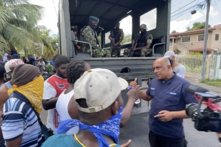 A police officer tries to persuade the scrap ironworkers not to block the roads, on Thursday 18 August 2022. (Image by IVAN TOOLSIE)