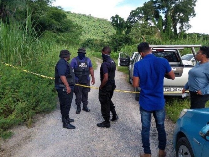 Chaguaramas Development Authority officers at Guave Road, off the Tucker Valley Road, Chaguaramas, following the discovery of the bodies of two bullet-riddled and bound men yesterday.