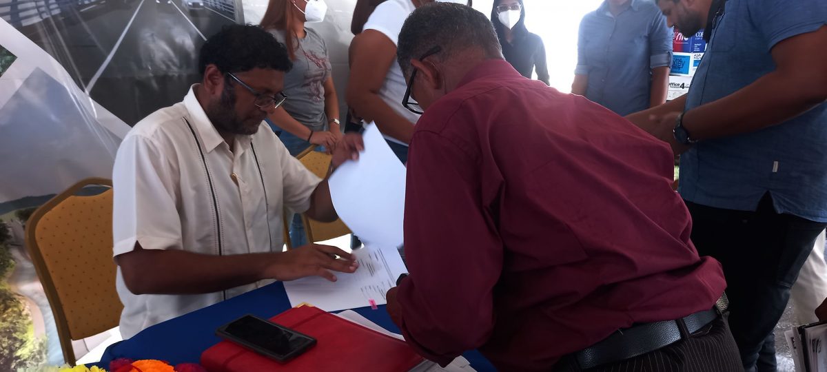Ministry of Public Works Permanent Secretary Vladim Persaud and a contractor going over one of the contracts signed on Friday at the Albion Sports Complex
