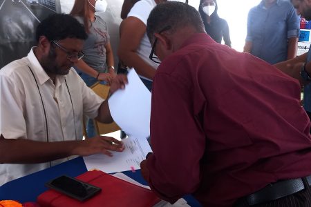 Ministry of Public Works Permanent Secretary Vladim Persaud and a contractor going over one of the contracts signed on Friday at the Albion Sports Complex
