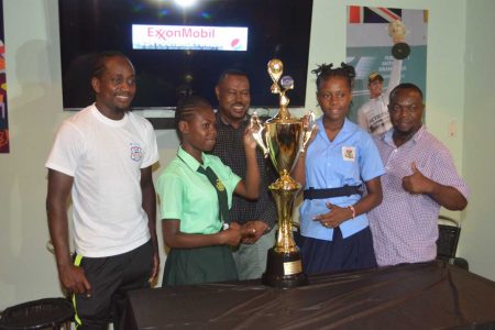 Chinwendu Rover (2nd from left), captain of Charlestown, and Azaria Wilson, skipper of East Ruimveldt pose with the championship trophy alongside Charlestown coach Ranole Bourne (left), and East Ruimveldt tactician Selwyn Browne (right). Also in the photo is Petra Organization Co-Director Troy Mendonca
