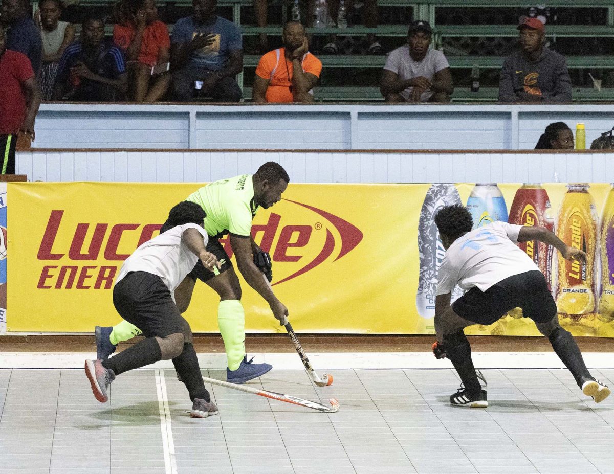 Shane Samuels (green) of Hikers Cadets on the attack against Hikers S-Team in the Lucozade Indoor Hockey Championship