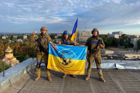 Ukrainian soldiers pose with a flag after retaking the town of Kupiansk near Kharkiv from Russian force, September 10, 2022.
