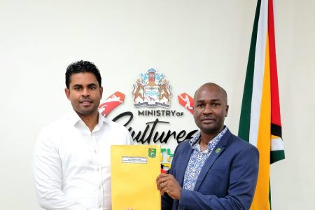 GFF President Wayne Forde (right) presenting the 2021 audited financial statements to Minister of Culture, Youth and Sport Charles Ramson Jr.