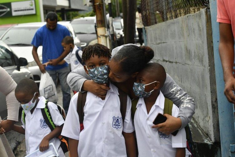 A mother hugs her sons before dropping them off at Arima Boys’ Government Primary School yesterday for the first day of the new term.