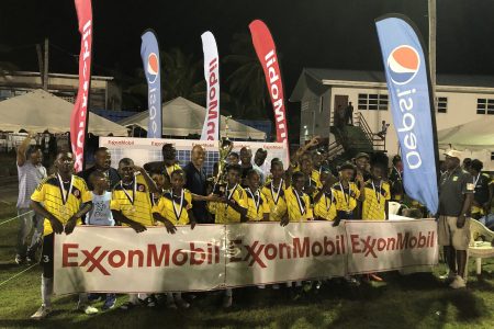 Marcus Tripp, Senior Director of Government and Public Affairs of ExxonMobil, presents the championship trophy to Charlestown captain Malcolm Hendricks in the presence of teammates, sponsors, and tournament officials