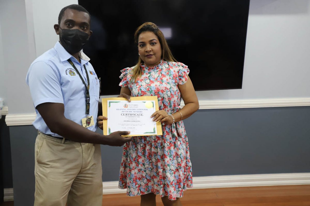 A Senior Inspector (left) presenting a Pesticide Vendor with her certificate. (Ministry of Agriculture photo)