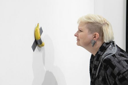 A fair visitor inspecting Maurizio Cattelan’s sculpture, Comedian, on Perrotin’s stand at Art Basel Miami (Photo: David Owens)