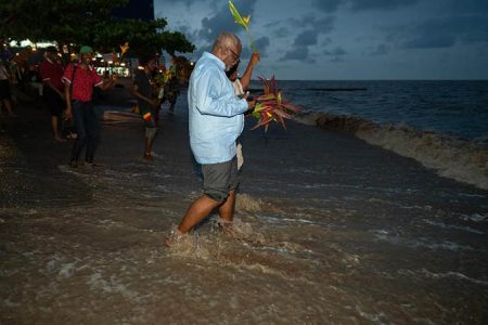 Prime Minister Mark Phillips and others honouring African ancestors with flowers and other offerings at the seawall. (Office of the Prime Minister photo)