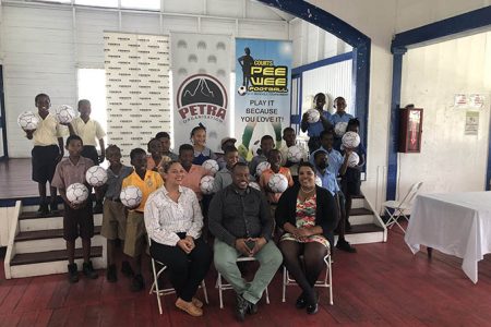 Several representatives from the competing schools posing with their footballs which were donated by the Petra Organization to aid their preparation. Also in the photo is (sitting from left) are Marketing Manager of Courts Guyana, Christel Van Sluytman, Petra Organisation Co-Director Troy Mendonca, and Petra Organization member Nareeza Latif