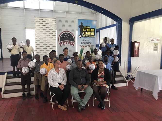 Several representatives from the competing schools posing with their footballs which were donated by the Petra Organization to aid their preparation. Also in the photo is (sitting from left) are Marketing Manager of Courts Guyana, Christel Van Sluytman, Petra Organisation Co-Director Troy Mendonca, and Petra Organization member Nareeza Latif