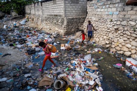 Two girls leap over a stream filled with trash in Port-au-Prince, Haiti October 13, 2022. REUTERS/Ricardo Arduengo